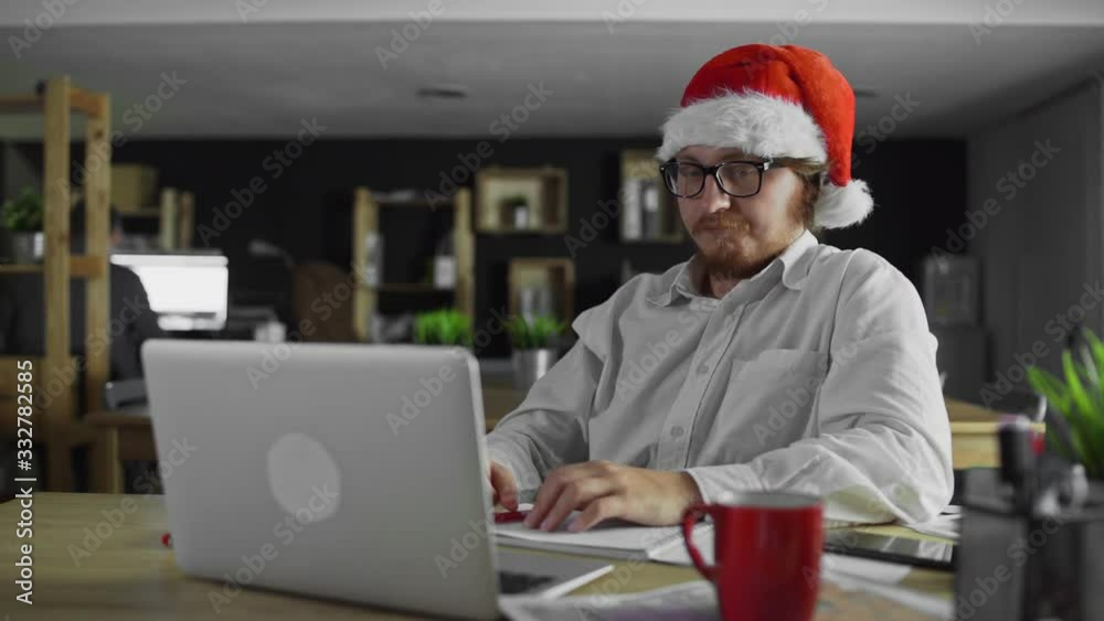 Young tired manager is working and drinking tea in Office on Christmas Young tired manager is working and drinking tea in Office on Christmas