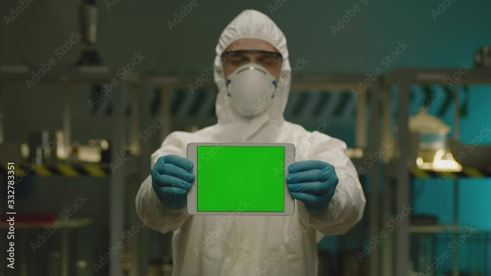 Doctor or researcher holds tablet PC with green screen to camera, standing in modern laboratory . Concept of medicine, technology, health care and people, hospital . Coronavirus , COVID-2019,  or H1N1