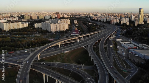 Aerial drone view of highway multi-level junction road with moving cars at sunset. Cars are moving on a multi-level road junction © Vit
