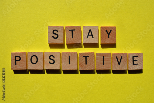 Stay Positive, words in wooden alphabet letters on yellow coloured background
