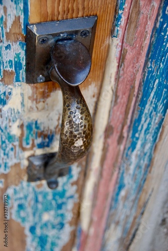 Vintage door handle on a weathered, peeling door. 