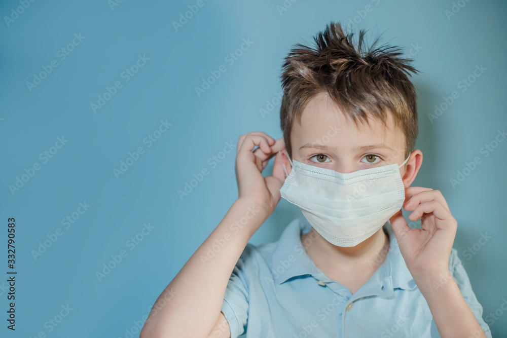 boy removes protective medical mask from face on blue background. child with flu, hantavirus or cold protected from viruses, pollution in bad epidemic situation, among patients with coronavirus boy removes protective medical mask from face on blue background. child with flu, hantavirus or cold protected from viruses, pollution in bad epidemic situation, among patients with coronavirus