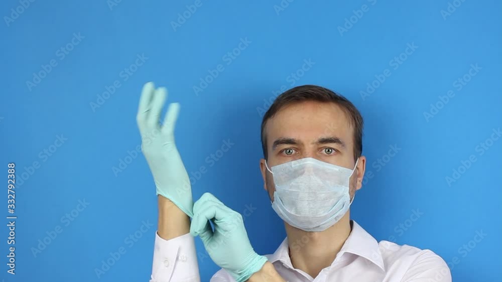 front view male face with medical mask, put on medical gloves, prevention or protection of virus coronavirus or pollution, doctor or patient demonstrate, blue background with copy space for titles front view male face with medical mask, put on medical gloves, prevention or protection of virus coronavirus or pollution, doctor or patient demonstrate, blue background with copy space for titles