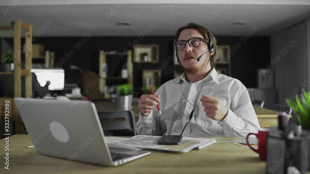 Manager in headphones is working at desk in office Manager in headphones is working at desk in office