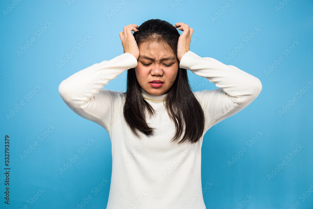 Portrait of Young beautiful asian women using white T-shirt with blue isolated background, headache Portrait of Young beautiful asian women using white T-shirt with blue isolated background, headache