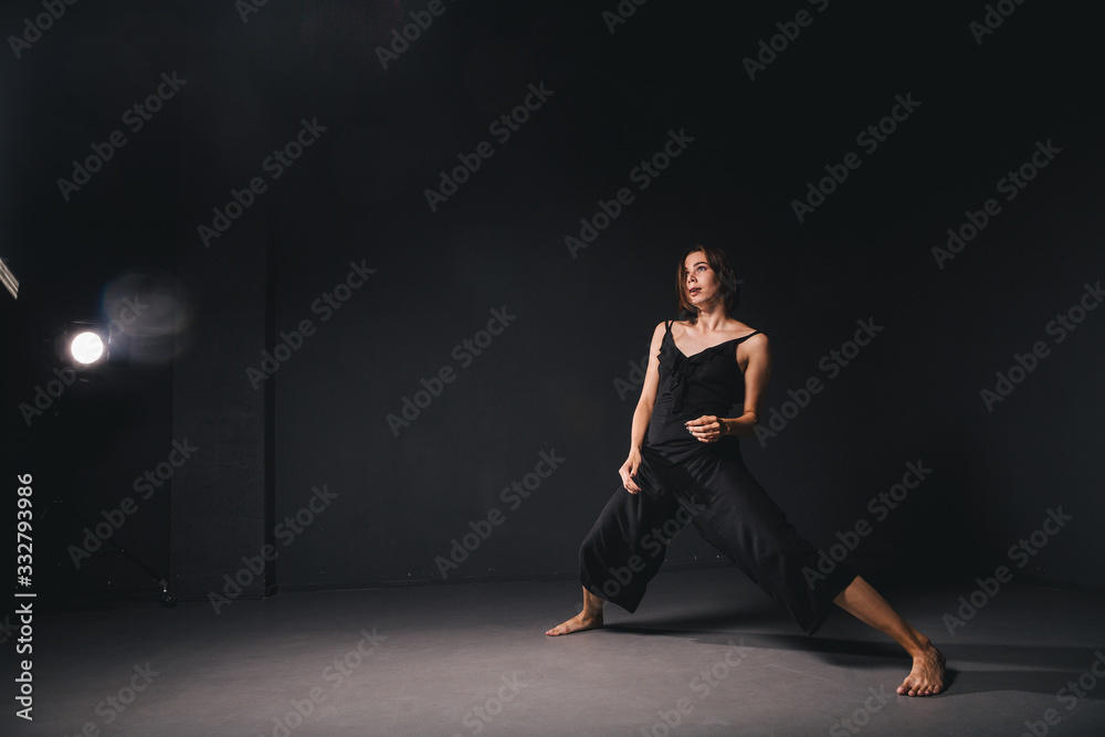 Portrait of a beautiful woman dancing on black background. Ballet and contemporary dancer dancing on dark backdrop. Contemporary Art. Plastic and flexible girl in black clothes posing on a black wall