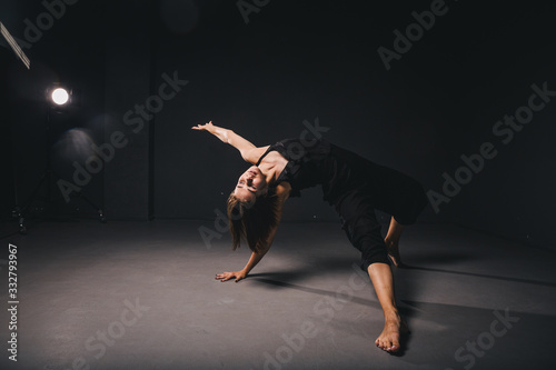 Portrait of a beautiful woman dancing on black background. Ballet and contemporary dancer dancing on dark backdrop. Contemporary Art. Plastic and flexible girl in black clothes posing on a black wall