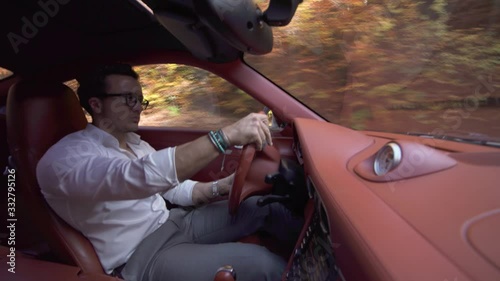 Close up of young handsome businessman driving a luxury car on the highway through mountain forest. Concept of business, success, traveling, luxury. photo
