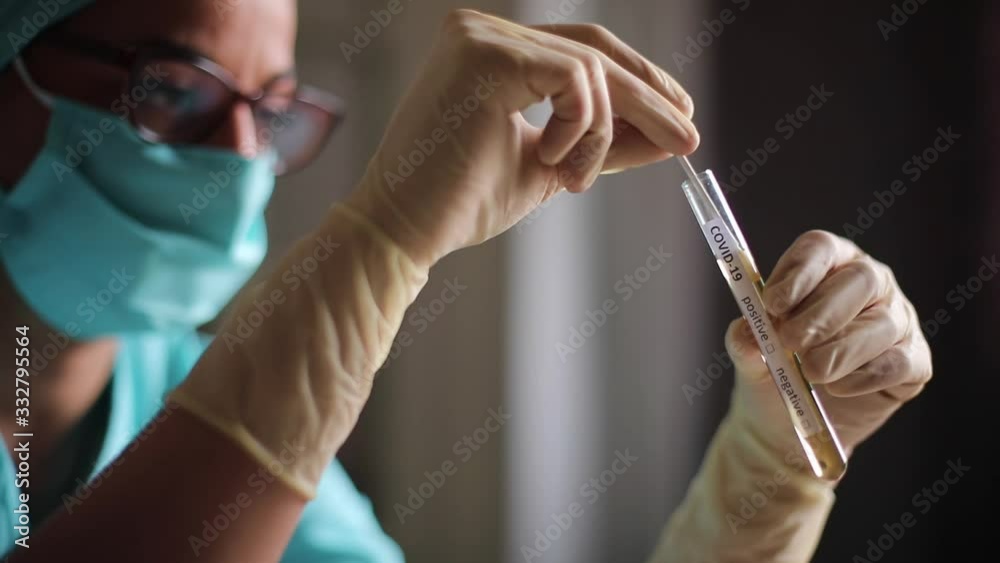 Conceptual video of a doctor holding and looking at a test tube while testing samples for presence of coronavirus (COVID-19).