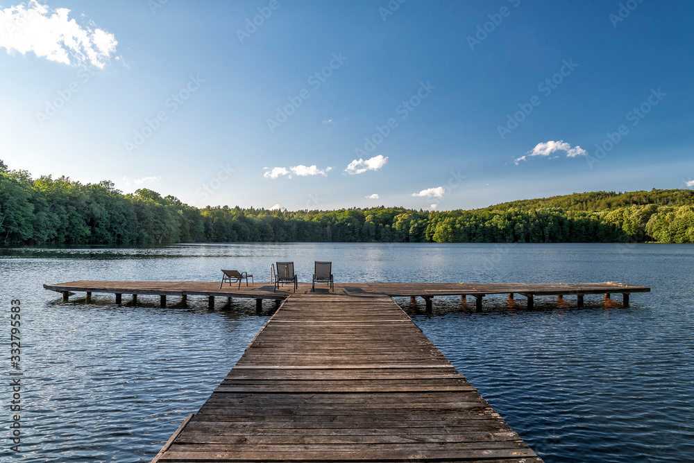 sommerlicher Badesee mit Steg und Liegestühlen