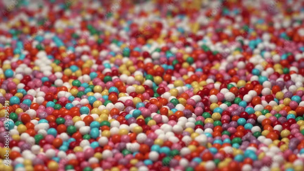 A lot of colorful sprinkles sugar candy lay on table. multi-colored dragee slow passing camera. Red blue green yellow white orange. A lot of colorful sprinkles sugar candy lay on table. multi-colored dragee slow passing camera. Red blue green yellow white orange.