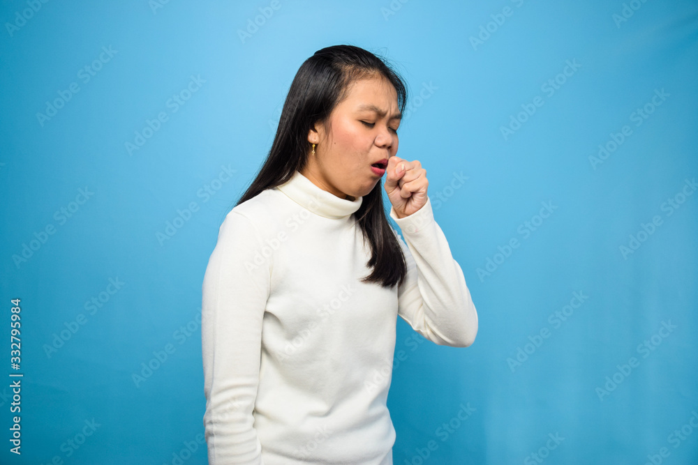 Portrait of Young beautiful asian women using white T-shirt with blue isolated background, coughing due to symptoms of corona virus, Covid-19, coughing coronavirus Portrait of Young beautiful asian women using white T-shirt with blue isolated background, coughing due to symptoms of corona virus, Covid-19, coughing coronavirus