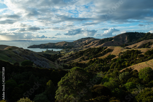 Sunset with clouds over sea and hills at Coromandel Peninsula