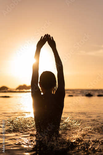 woman practicing yoga on beach at sunset