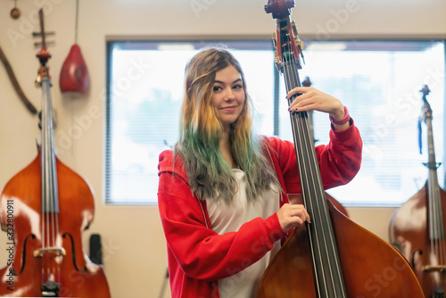 Portrait of smiling teenage girl playing double bass in classroom photo