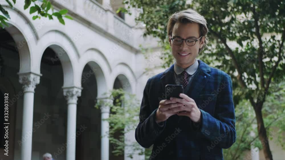 Student using smartphone on university territory. Man typing on phone phone Student using smartphone on university territory. Man typing on phone phone