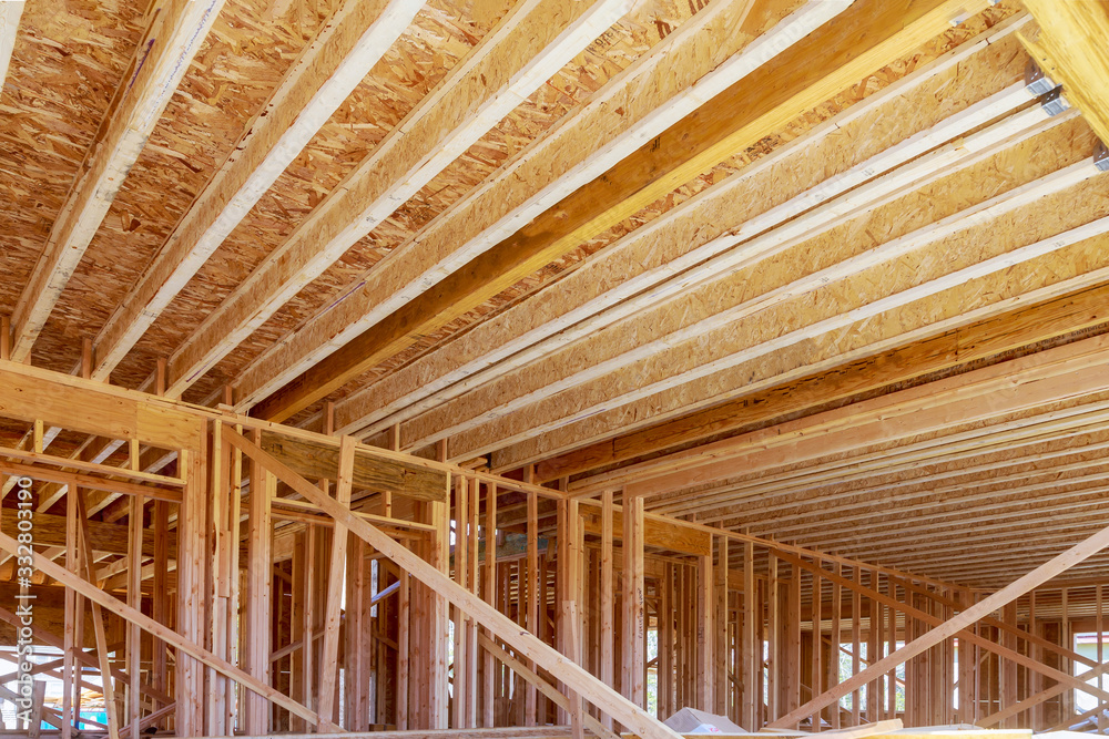 Condominium building with under construction wooden house with timber framing, truss, joist, beam Condominium building with under construction wooden house with timber framing, truss, joist, beam