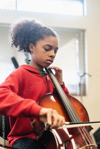 Teenage girl playing cello in classroom