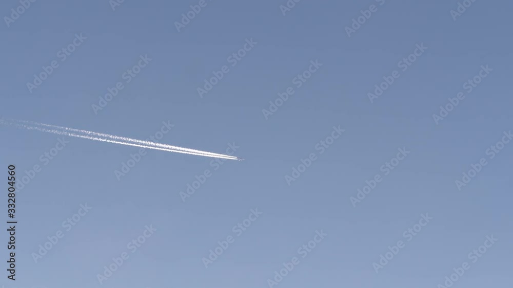 Static shot of airplane leaving Vapor Trail In blue cloudless Sky Static shot of airplane leaving Vapor Trail In blue cloudless Sky