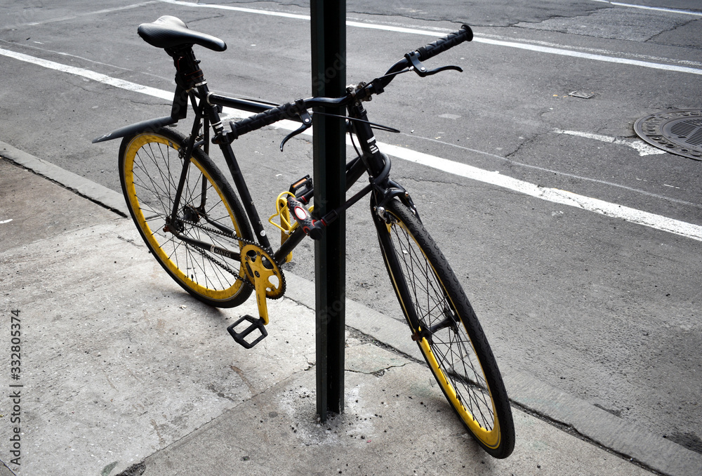 Yellow bicycle chained to a pole on a street in Manhattan, New York