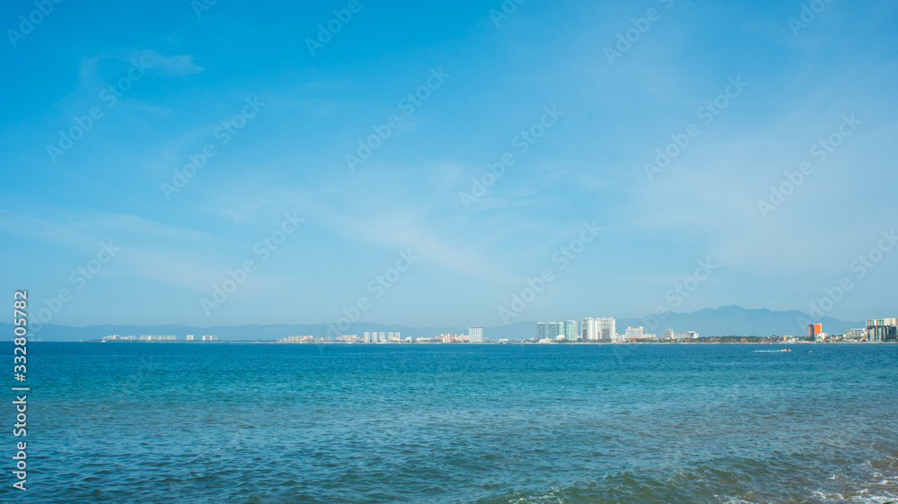 Bright Blue Ocean Beach With Buildings in the Background In Puerto Vallarta Mexico