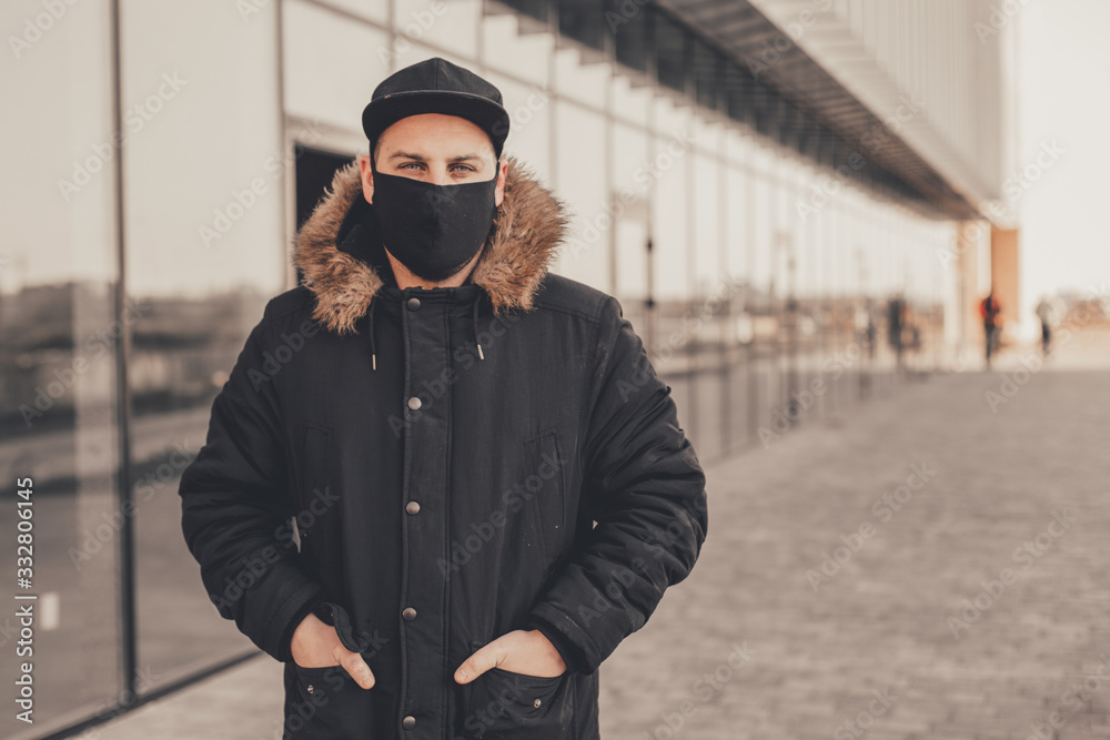 Men wears a black protective medical face mask being in the city during a coronavirus pandemic. Protection from viruses in the city. Men wears a black protective medical face mask being in the city during a coronavirus pandemic. Protection from viruses in the city.