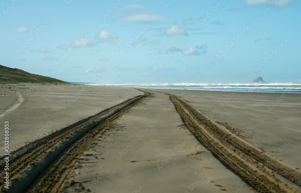 Tire tracks on beach with sea in the background near Cape Reinga New Zealand