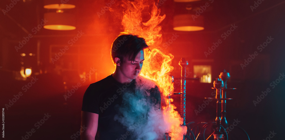 man is relaxing and Smoking a hookah and blowing a cloud of smoke in a lounge cafe man is relaxing and Smoking a hookah and blowing a cloud of smoke in a lounge cafe