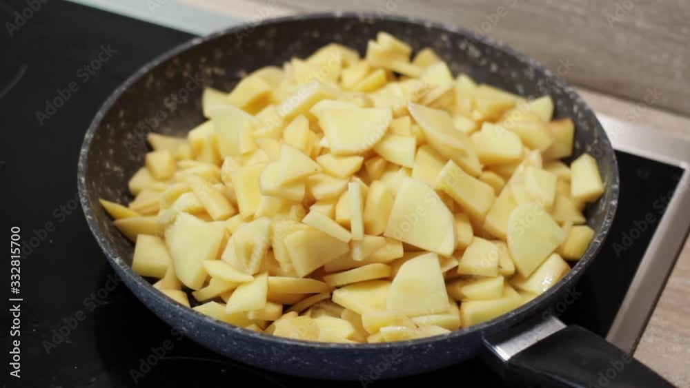 Cooking chopped up russet potatoes in black skillet on stove, close up Cooking chopped up russet potatoes in black skillet on stove, close up