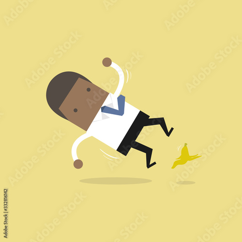African businessman slipping on a banana peel and falling down.