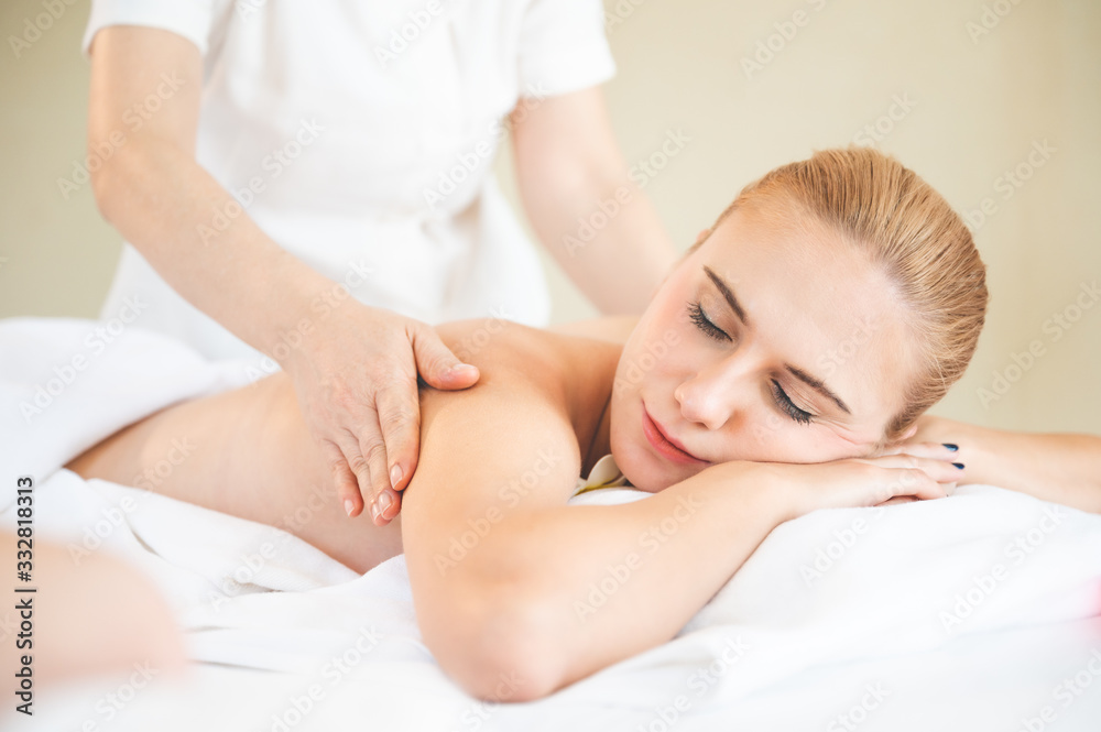 Health care and thai massage. Beautiful woman getting back and shoulder massage in spa salon