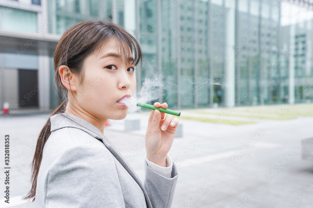 電子タバコを吸う若いビジネスウーマン 電子タバコを吸う若いビジネスウーマン