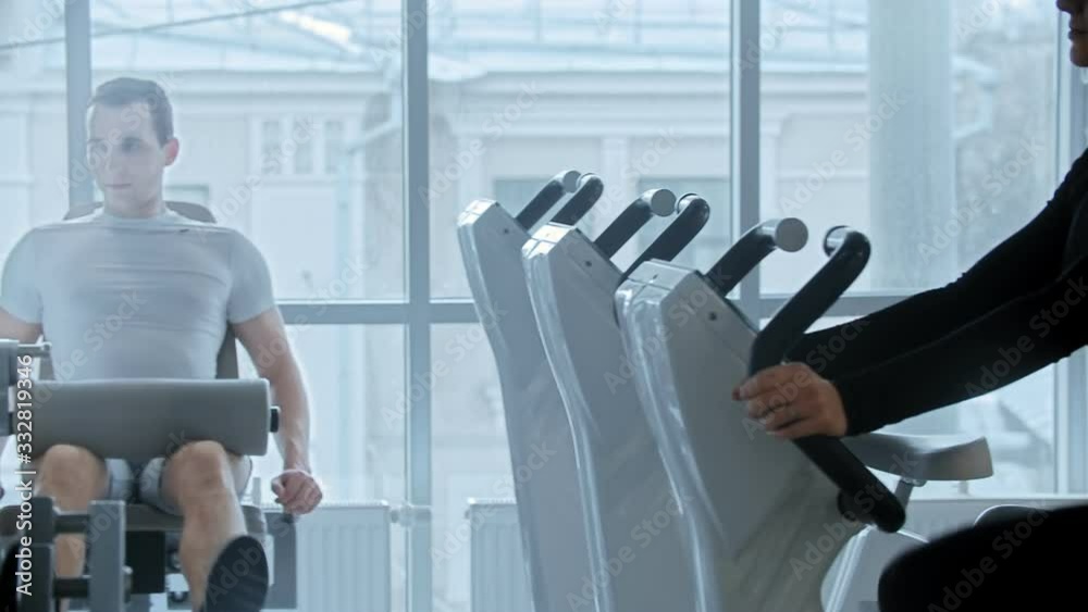 Modern gym - young man and woman training in white modern gym with panoramic mirrors Modern gym - young man and woman training in white modern gym with panoramic mirrors