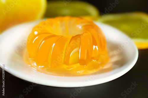 round sweet yellow jelly in a white plate on a background of oranges close up photo