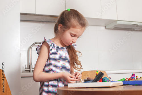 7 years old baby craft with plasticine in the kitchen. Home interior. Home education.