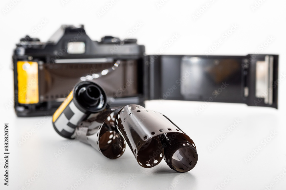 Single lens reflex camera and a film roll on a white background. Single lens reflex camera and a film roll on a white background.