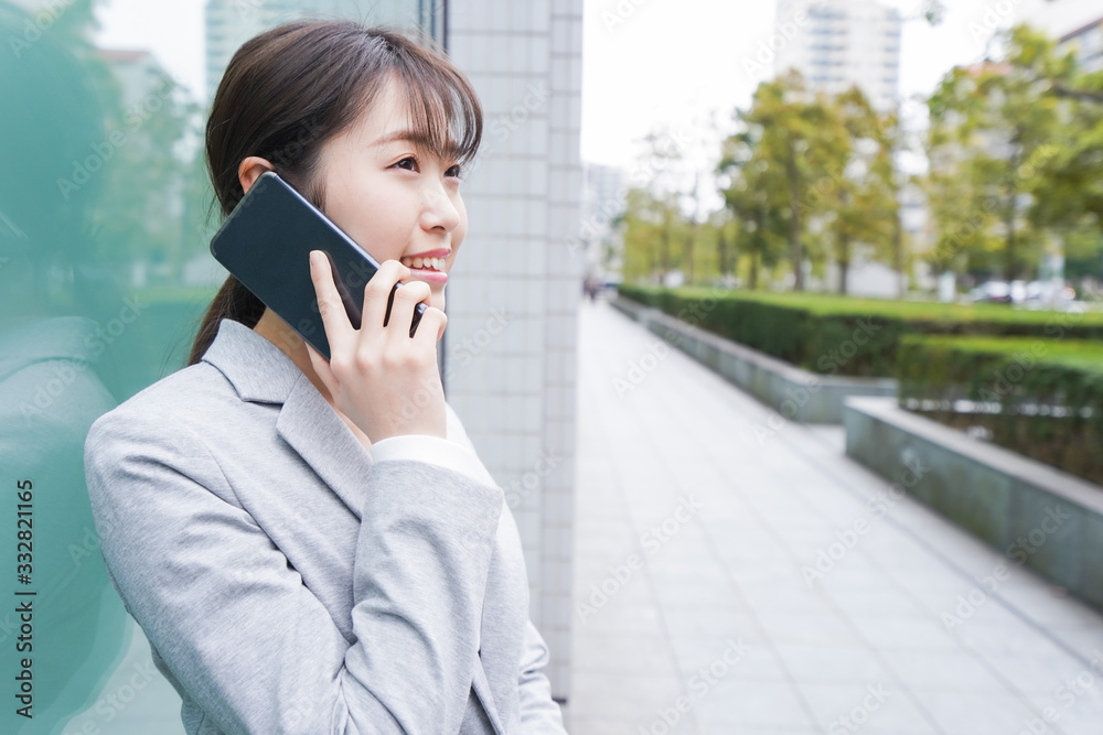 オフィス街で電話をする若いビジネスウーマン オフィス街で電話をする若いビジネスウーマン
