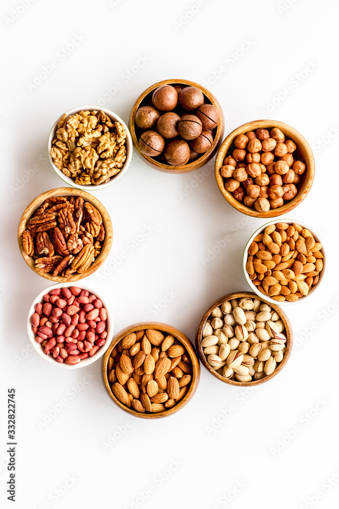 Nuts set in bowls on white background top-down frame copy space Nuts set in bowls on white background top-down frame copy space