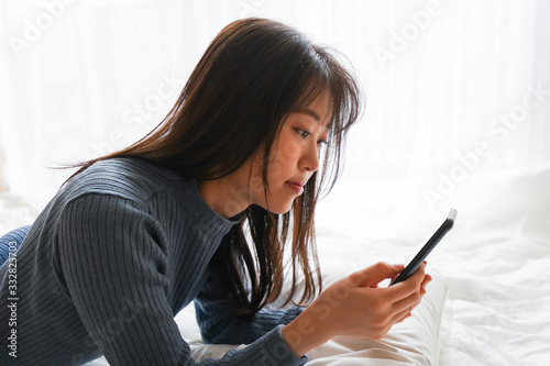 ベッドで寝る前にスマホを使う若い女性