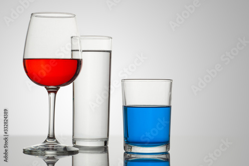 Copa y vasos de cristal con un fondo blanco y bebidas de diferentes tipos y colores, con composiciones atractivas