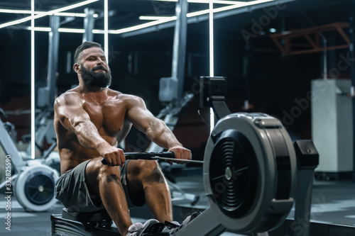 Young strong bearded bodybuilder doing low cable pulley row seated