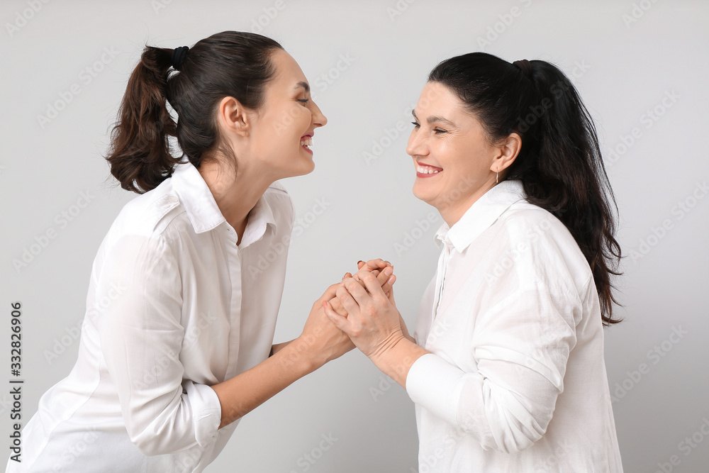 Portrait of adult daughter and her mother on grey background Portrait of adult daughter and her mother on grey background