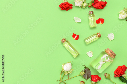 Bottles with rose essential oil on color background