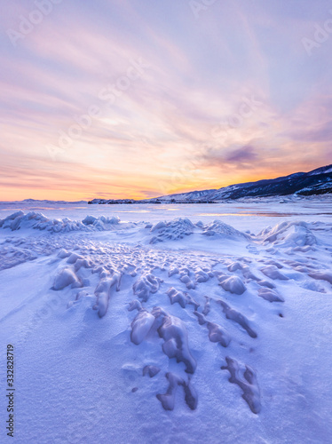 Frozen winter landscape of ice on lake Baikal during a colorful sunset. Lake Baikal, Siberia, Russia.