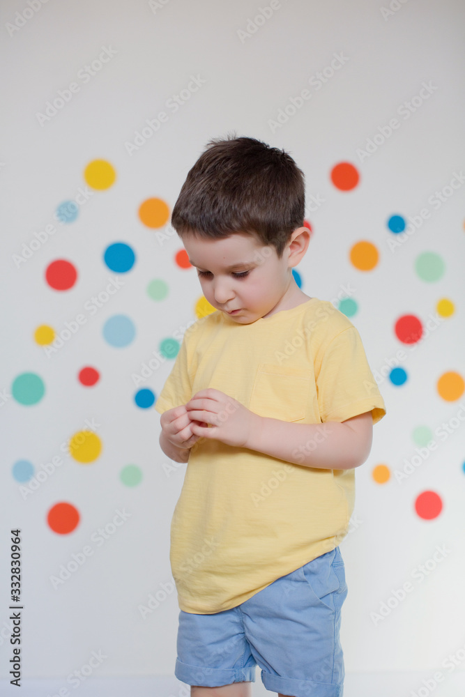 Sad toddler boy on a background of wall with colorful circles