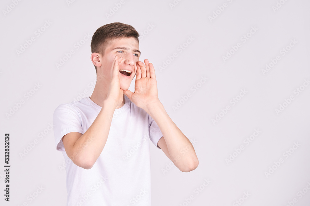 Happy teen man yelling loud. Fun voice concept. Adorable boy portrait. Male sale emotion. Shouting with hands near mouth. Happy teen man yelling loud. Fun voice concept. Adorable boy portrait. Male sale emotion. Shouting with hands near mouth.