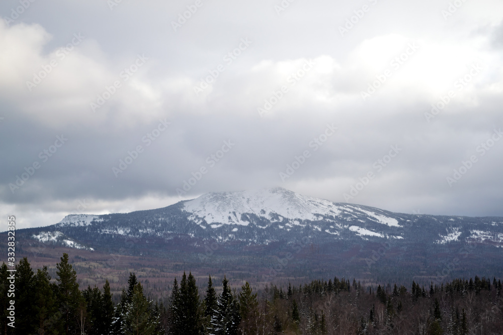 Nature landscape. Snowy mountain top closed by white cumulus clouds