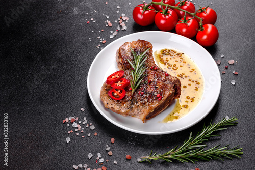 Fresh delicious juicy steak on the bones with vegetables and spices against a dark background