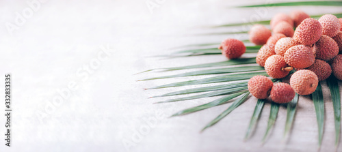 Lychee fruits with palm leaves on rattan background. Copy space. Exotic litchi, lichee fruits. Tropical food concept. photo