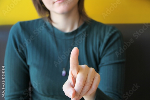 Foto Girl holds index finger in front of her, points towards the viewer and camera